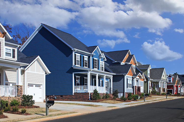Neighborhood of newly built homes in varying colors with blue sky and some clouds
